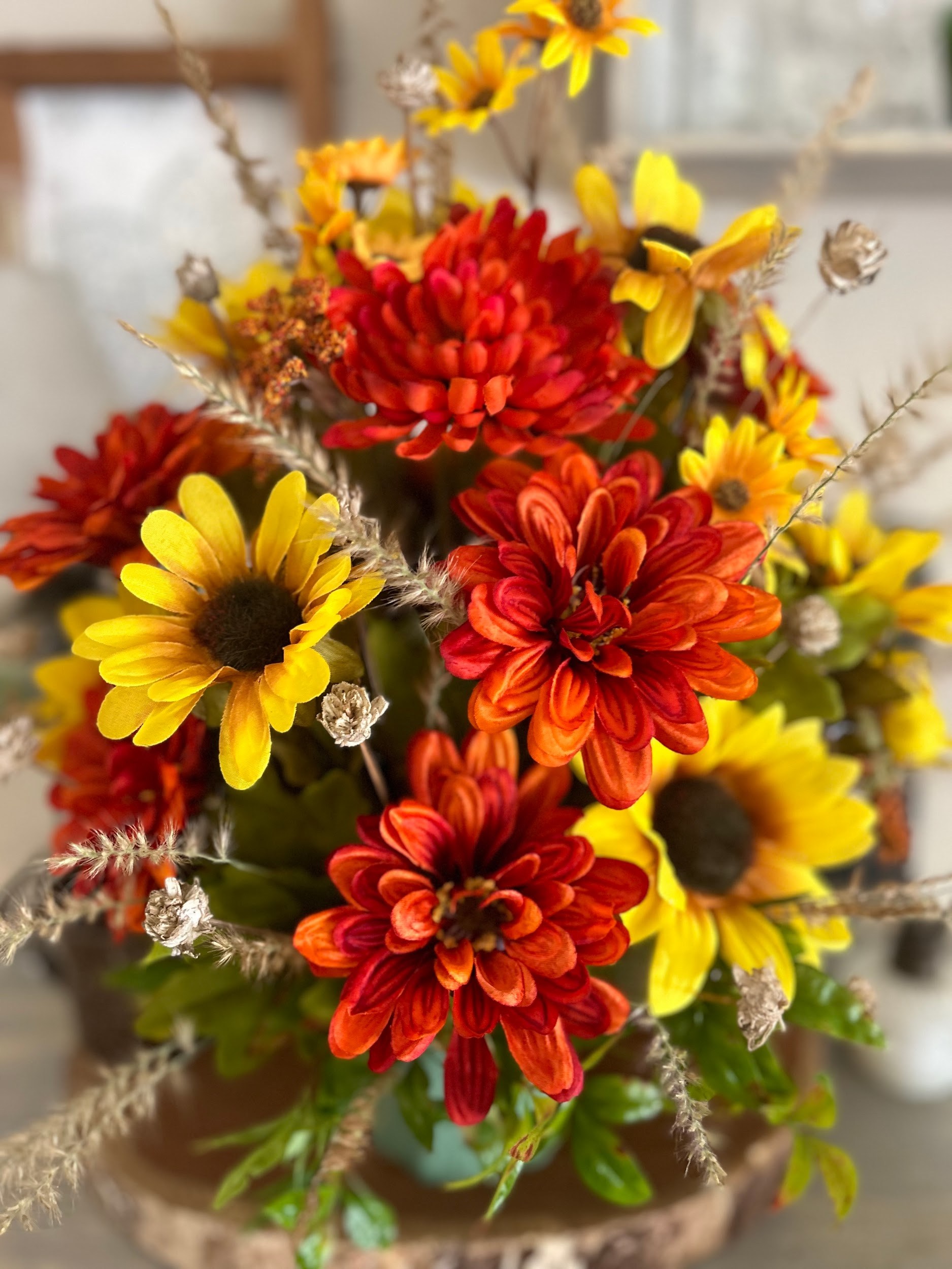 A vase filled with red , yellow and orange flowers on a table.