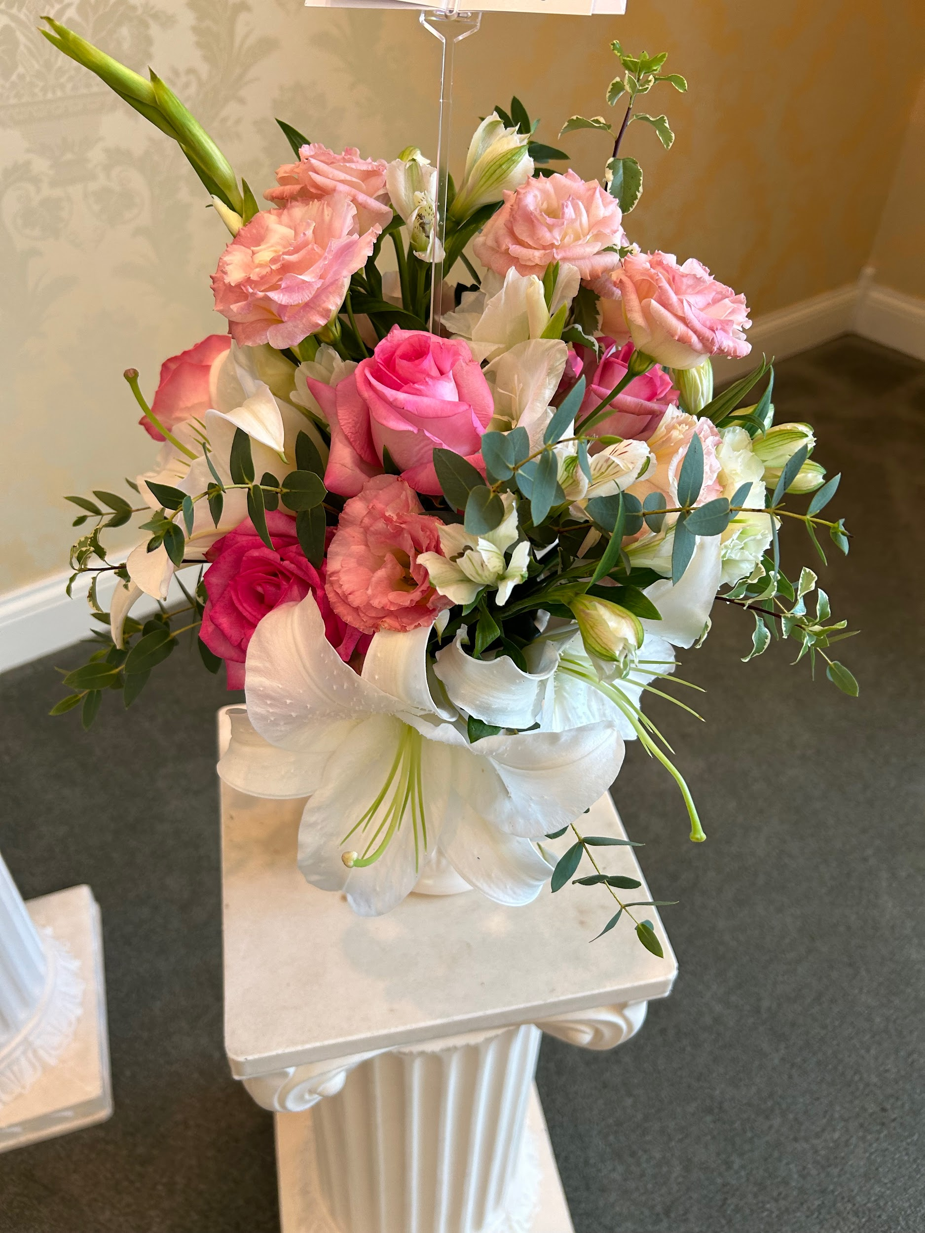 A vase filled with pink and white flowers is sitting on a pedestal.