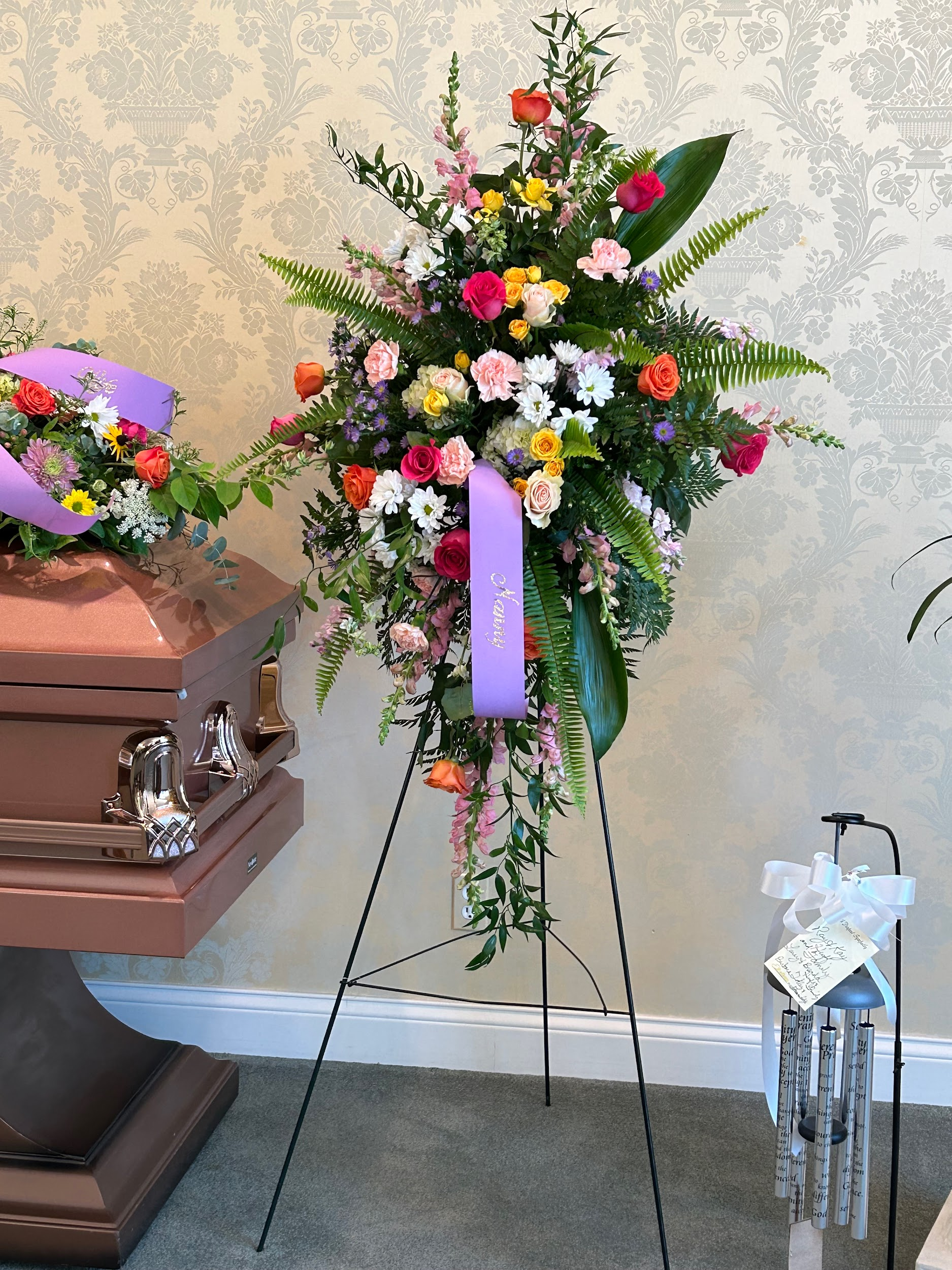 A coffin with flowers and a purple ribbon on it