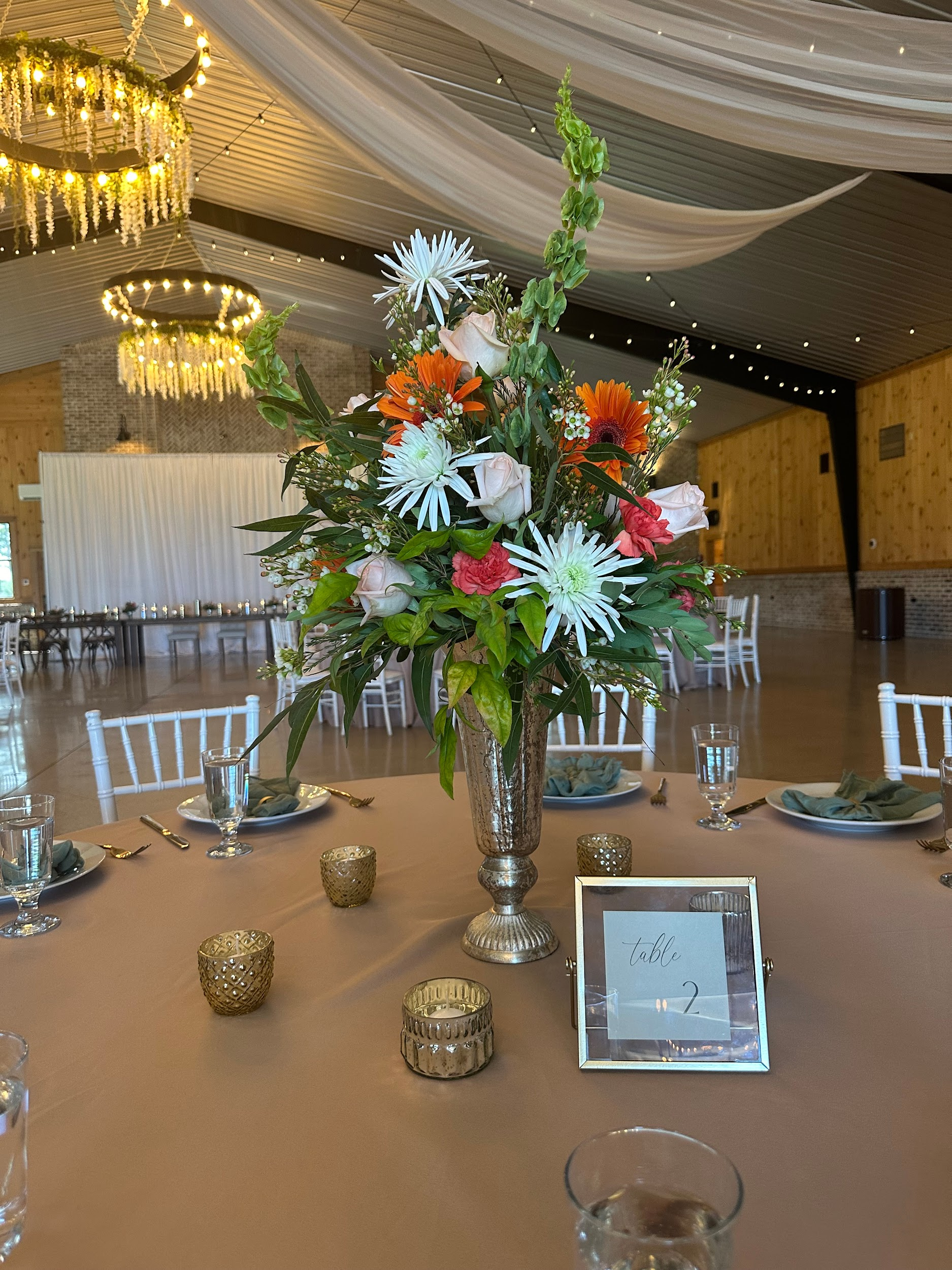 A table set for a wedding reception with a vase of flowers on it.