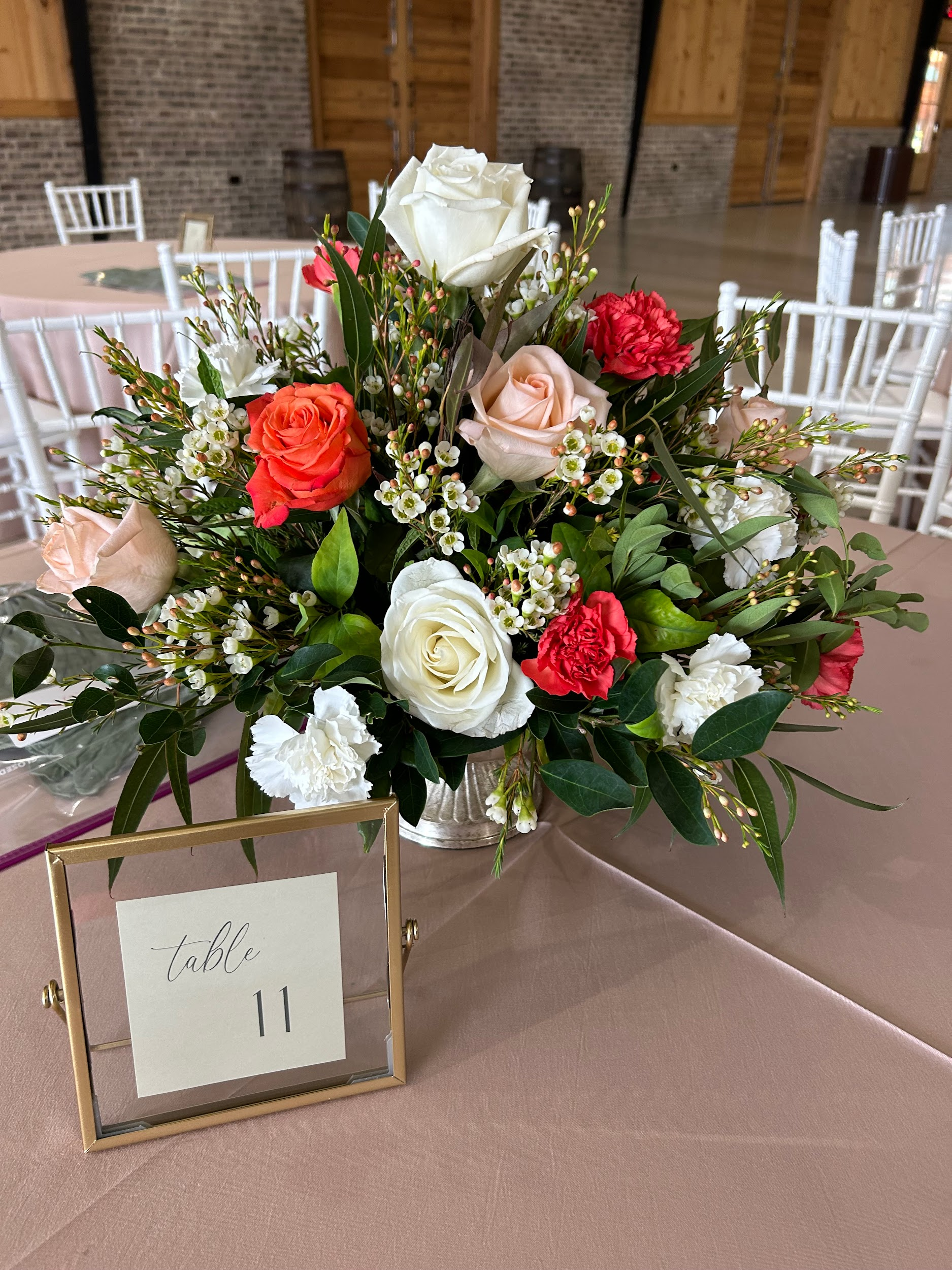 A table with a vase of flowers and a table number on it.