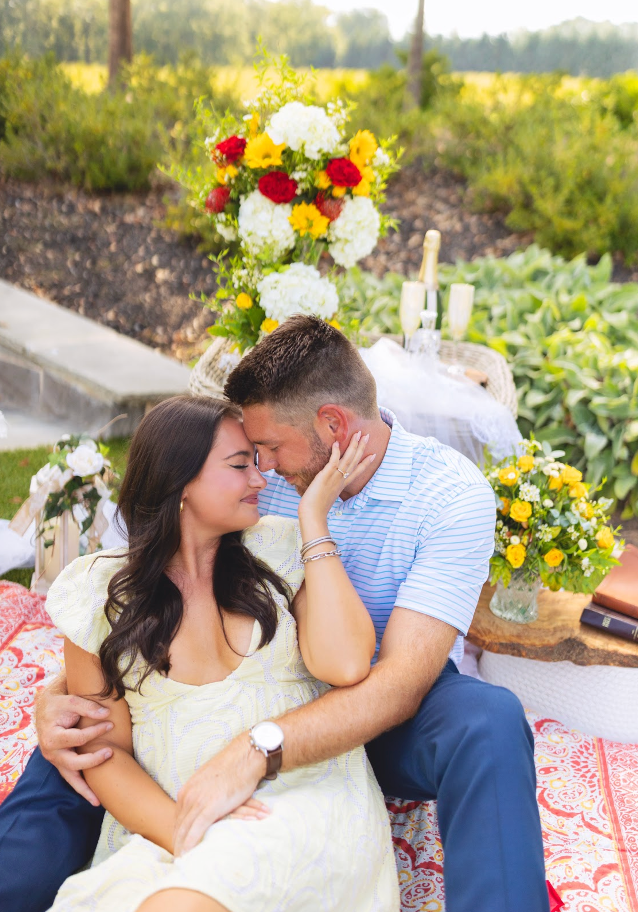 A woman is arranging flowers on a wooden table.