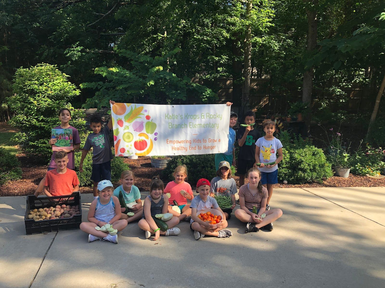 A group of children are sitting on the sidewalk eating watermelon.