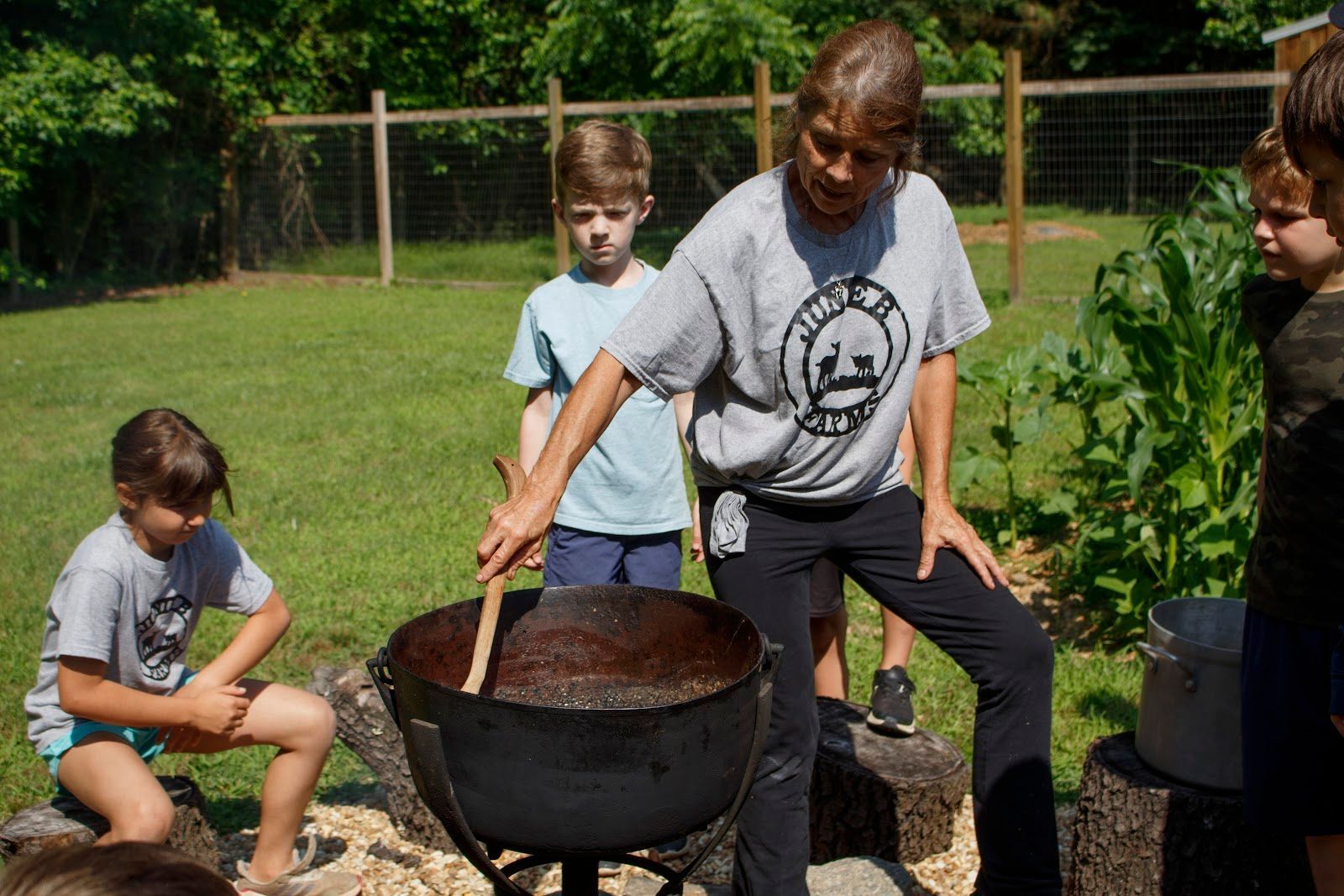 A group of children are sitting around a large pot.