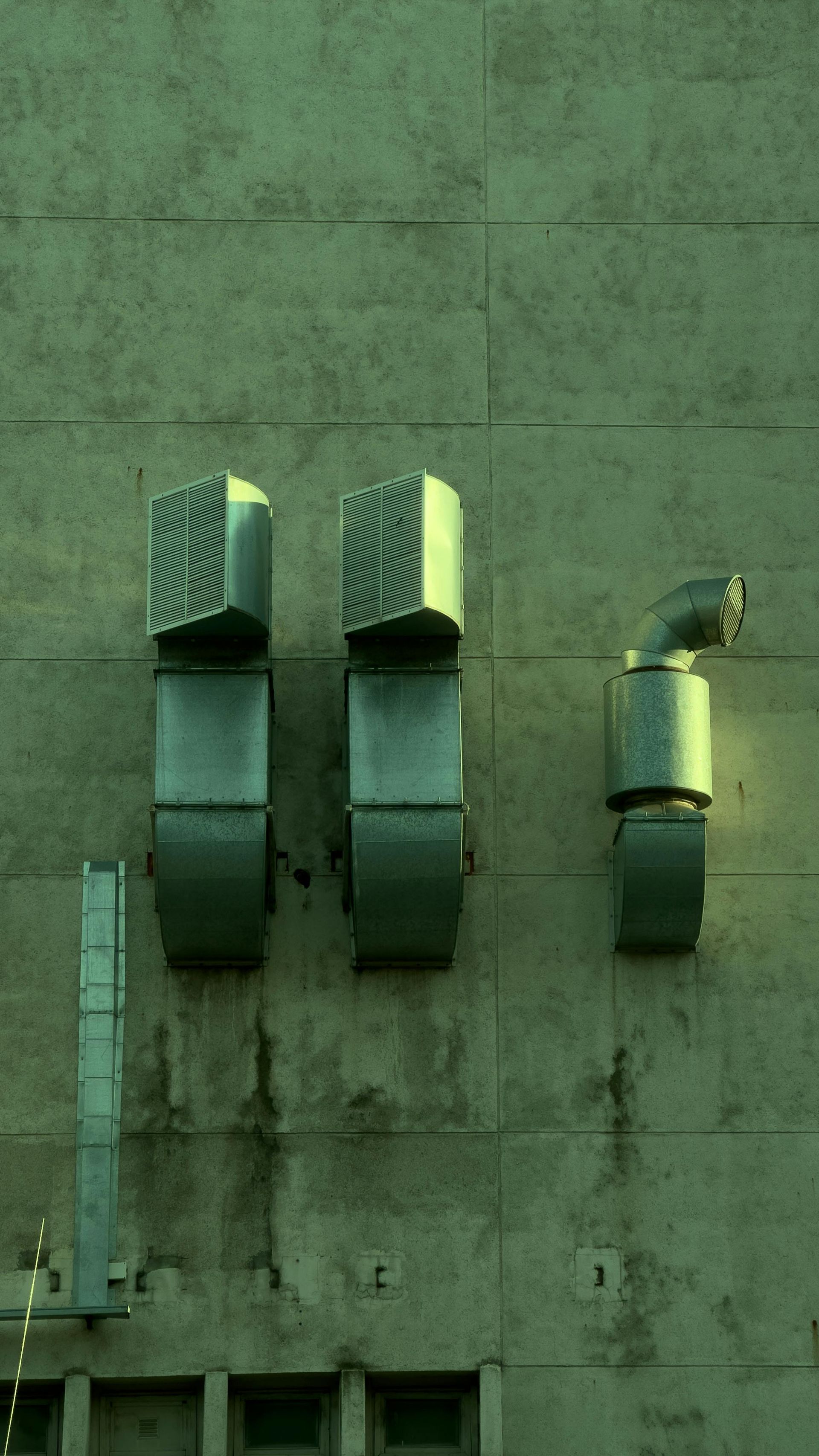 A row of exhaust pipes on the side of a building.