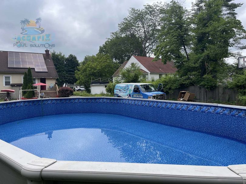 A blue van is parked in front of a swimming pool.