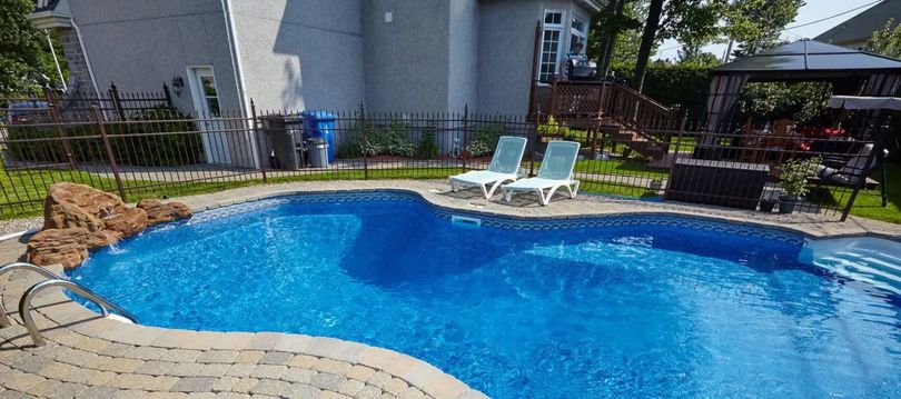 There is a large swimming pool in the backyard of a house.