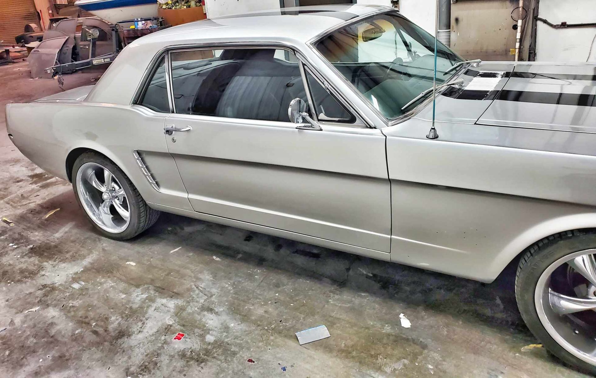 A silver and black mustang is parked in a garage