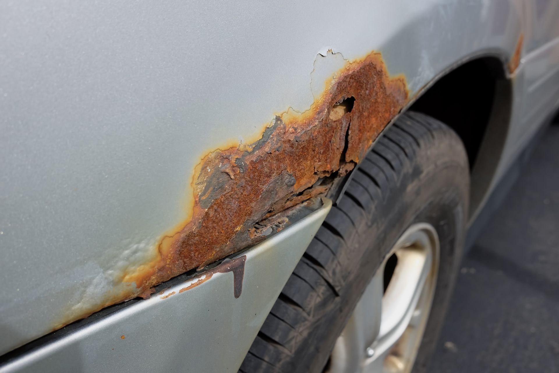 A close up of a rusty car fender and tire.