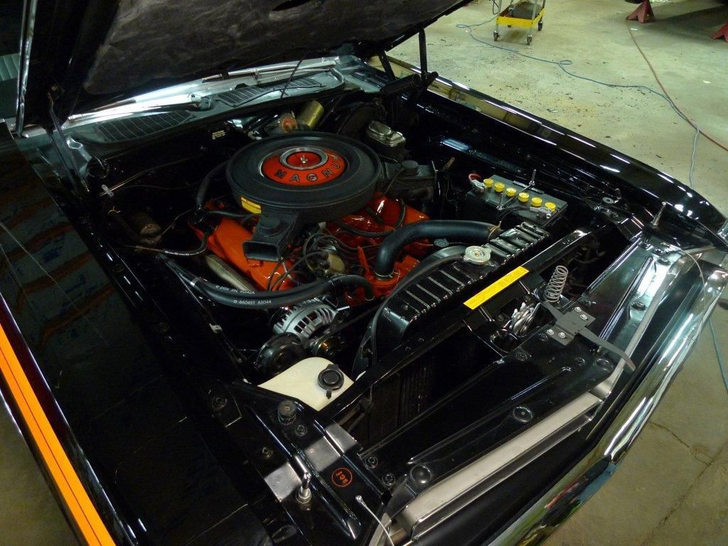 Black car engine bay with red engine block, orange air filter.