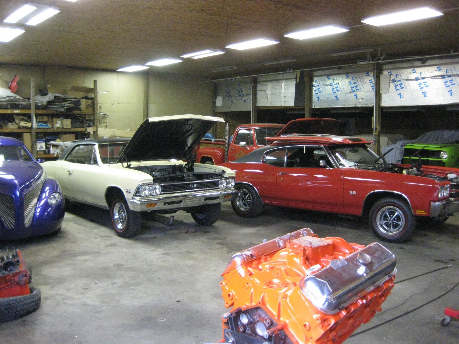 Classic cars inside a garage with an open engine.
