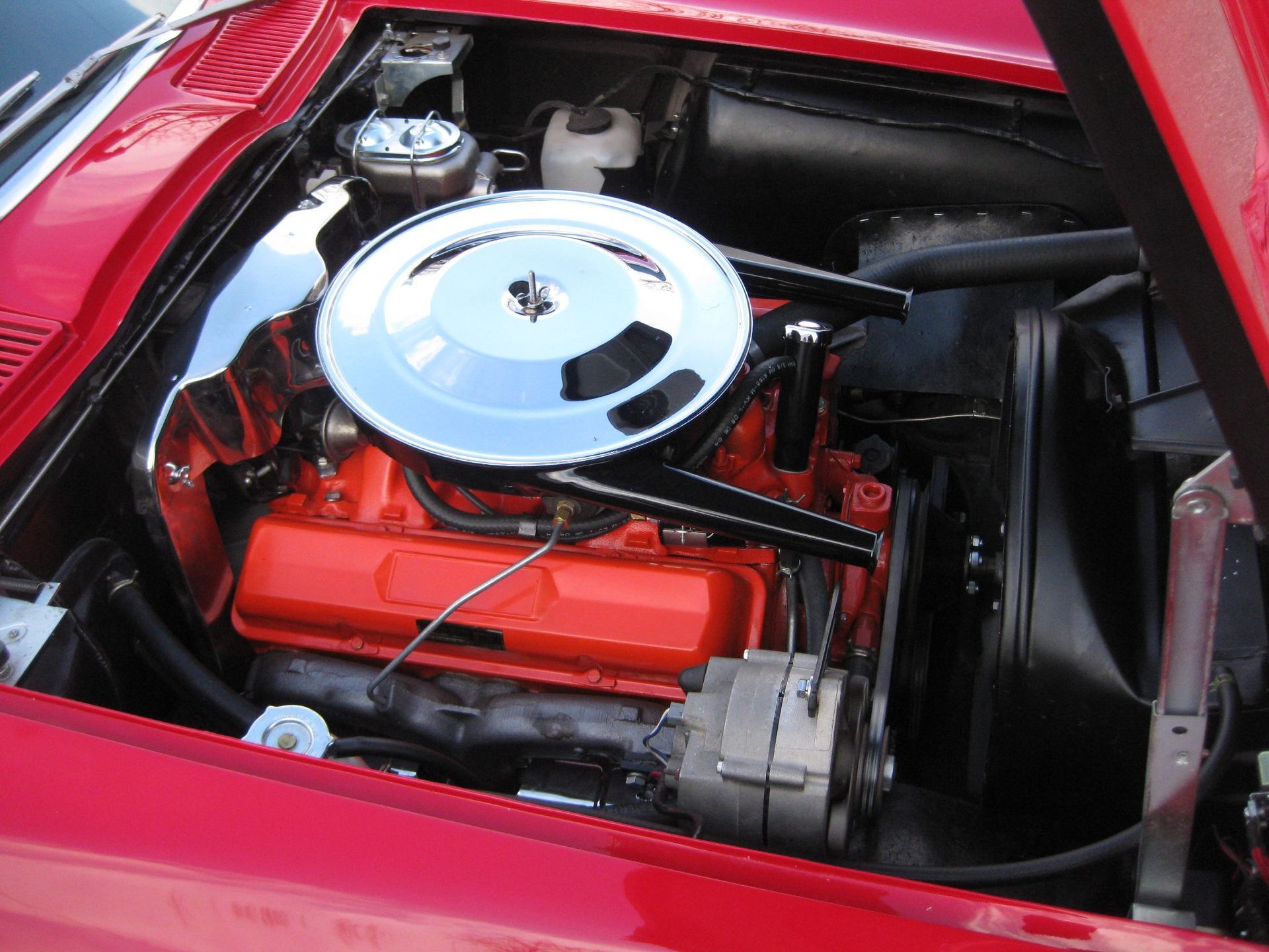 Red classic car engine with chrome air filter, bright red engine block.