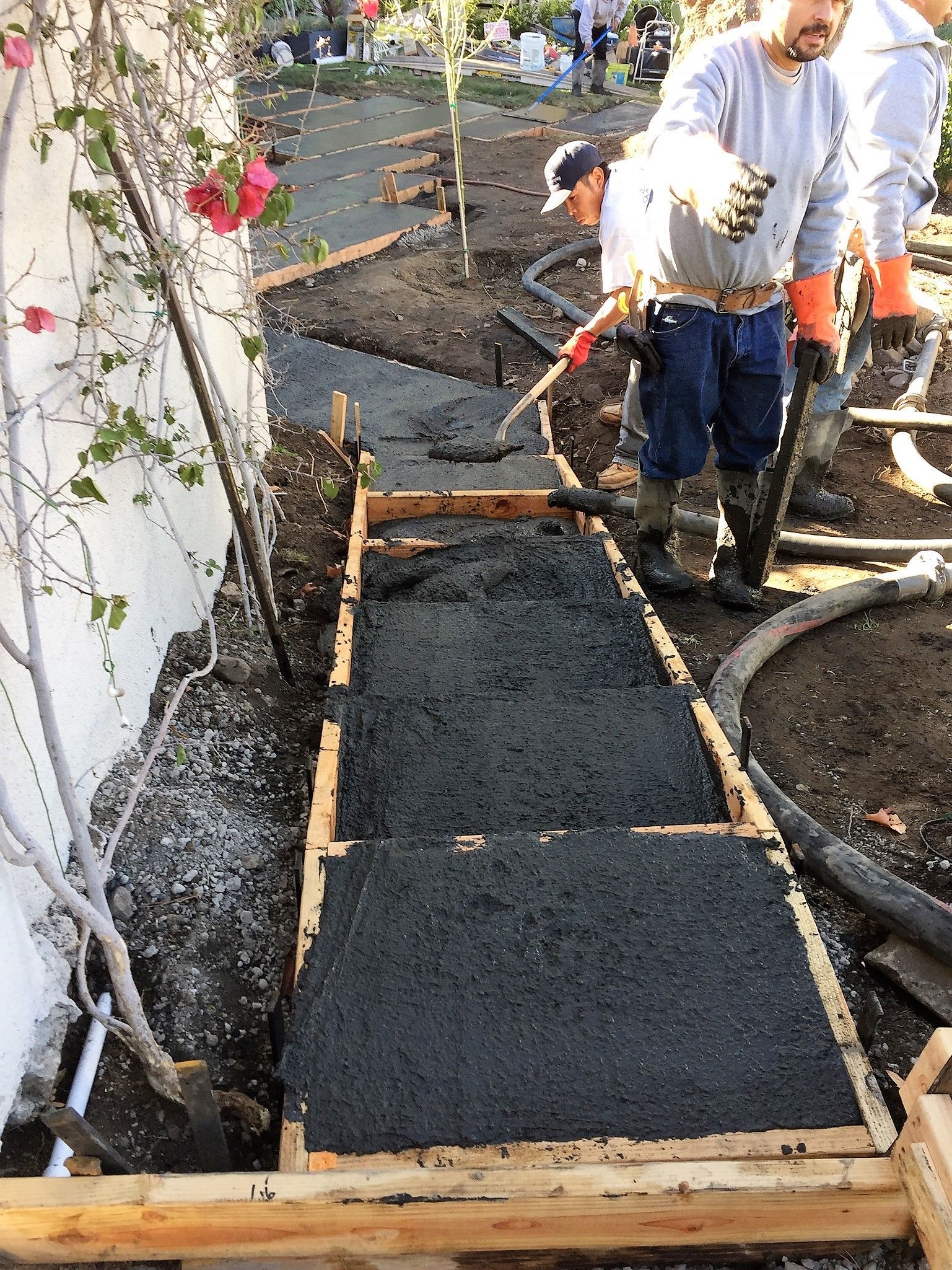 A group of men are working on a sidewalk.