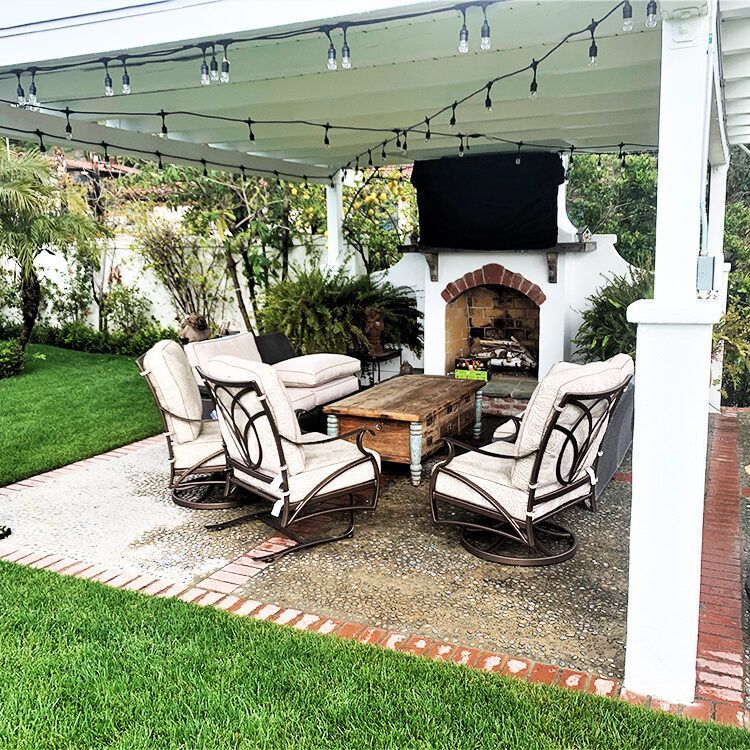 A patio with chairs and a fireplace under a canopy
