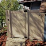 A wooden fence with a gate in front of a house.