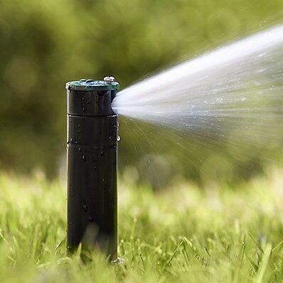 A sprinkler is spraying water on a lush green field.