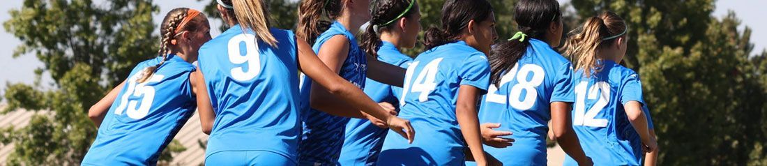 Baseball glove with ball on green grass, with blurred baseballs in the background.