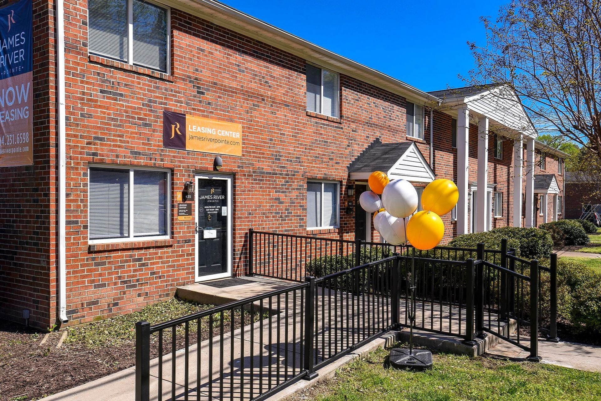 Brick apartment building with entrance, black railings, and balloons.