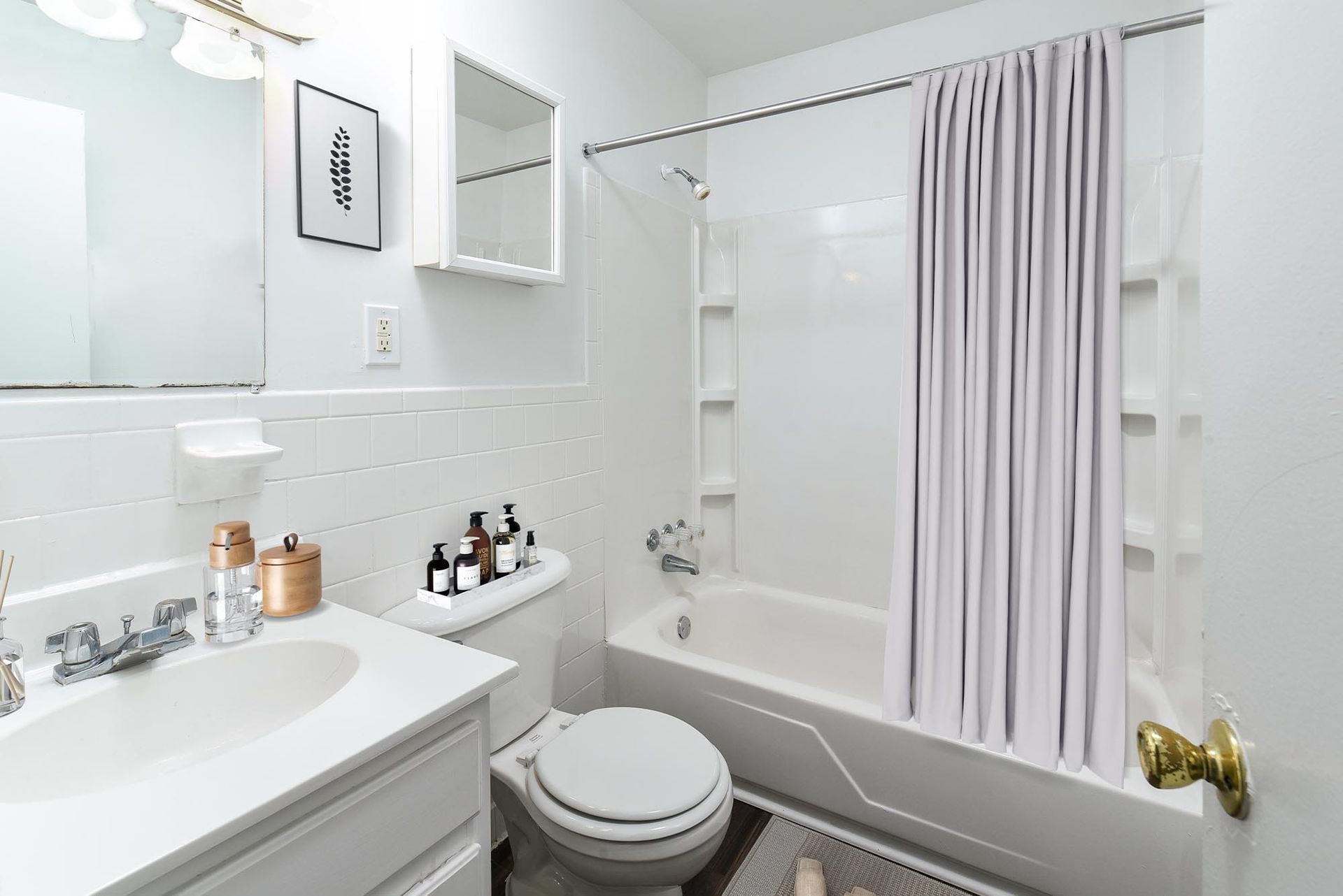White bathroom with a bathtub, toilet, sink, and shower curtain.