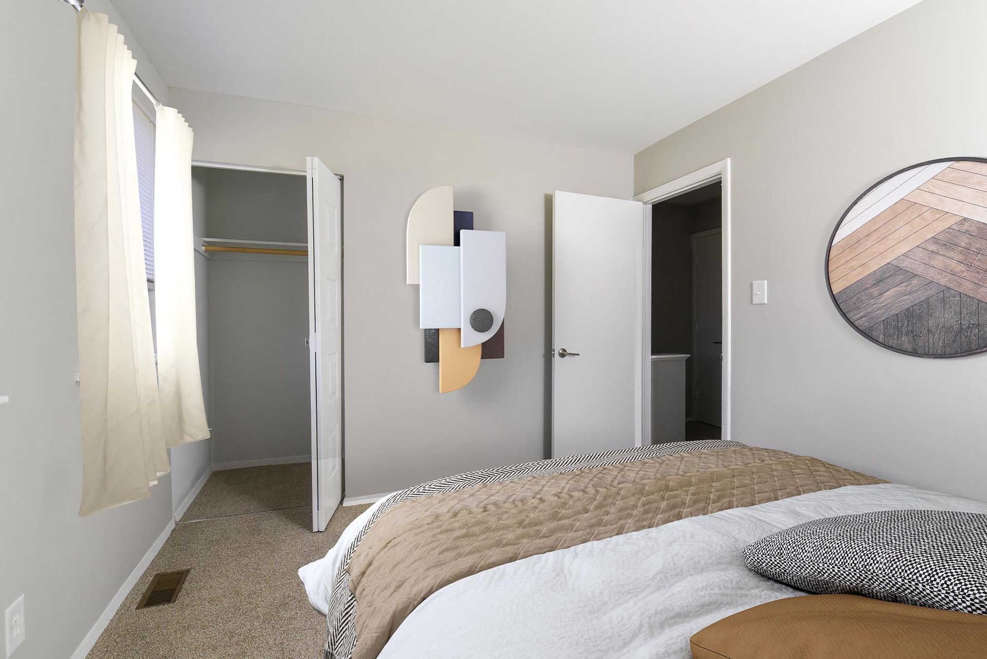 Bedroom interior with a bed, art piece, open closet, and a closed door.