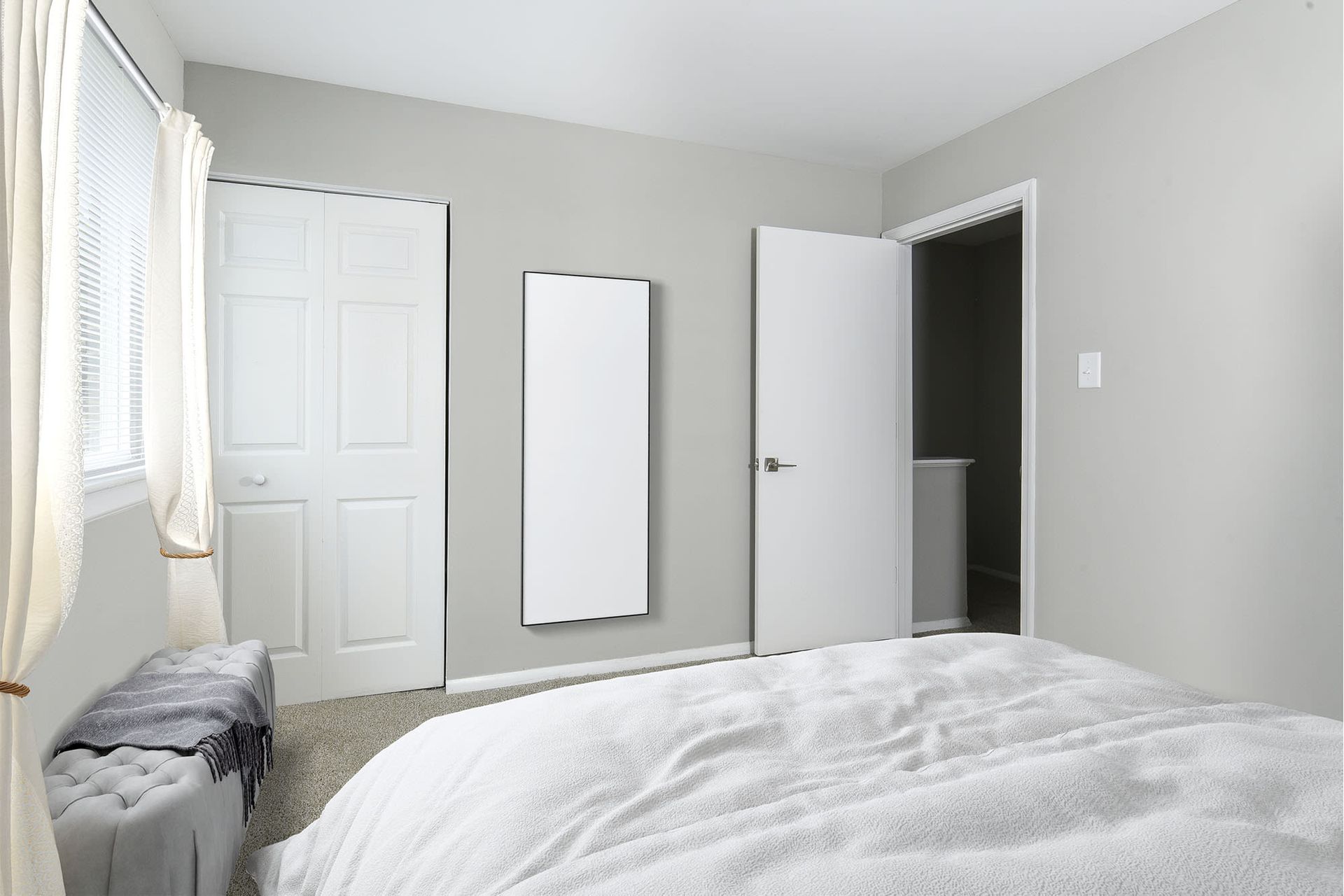 Bedroom with bed, closet, bathroom door, and a full-length mirror. Grey walls and white bedding.