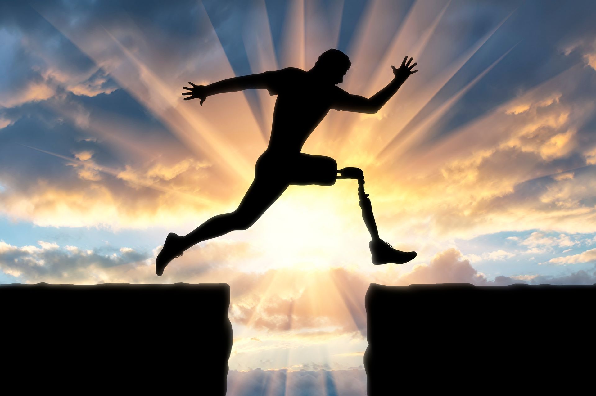 A man with a prosthetic leg is jumping over a cliff. Text overlaid reads improving lives building futures. At N-able Services, we're dedicated to transforming lives through bespoke rehabilitation and case management services, expertly tailored to support individuals with brain and spinal injuries, neurological conditions, and more. Let's build a brighter future together.