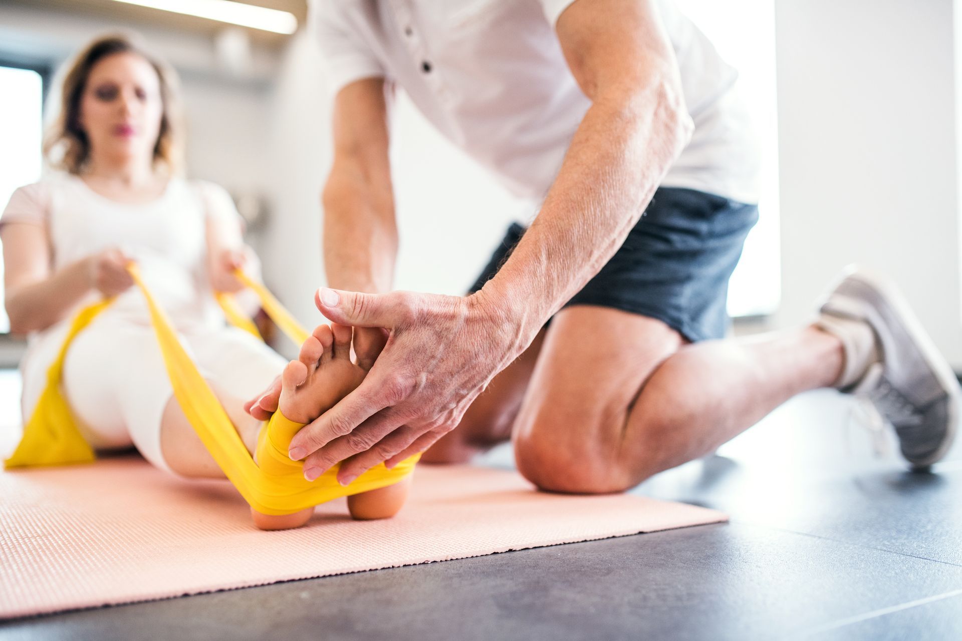 A man is stretching a woman 's leg with a rubber band. Text overlaid reads immediate needs assessments. Start your journey to recovery with our Immediate Needs Assessments – personalised, compassionate guidance to navigate the path ahead with confidence and ease.