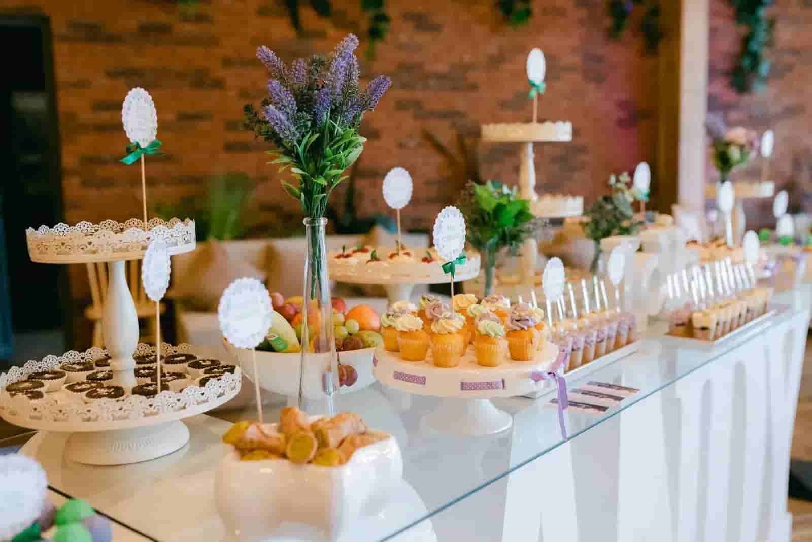 Dessert buffet with pastries, fruit tarts, and cupcakes on a white table at a wedding reception