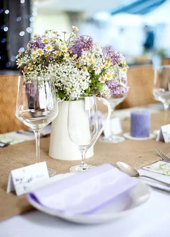 Flower centerpiece in white vase on a decorated banquet table with wine glasses