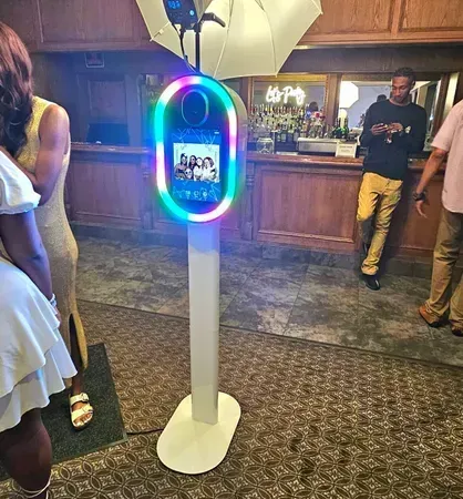 Colorful photo booth kiosk in a carpeted indoor event space with people nearby