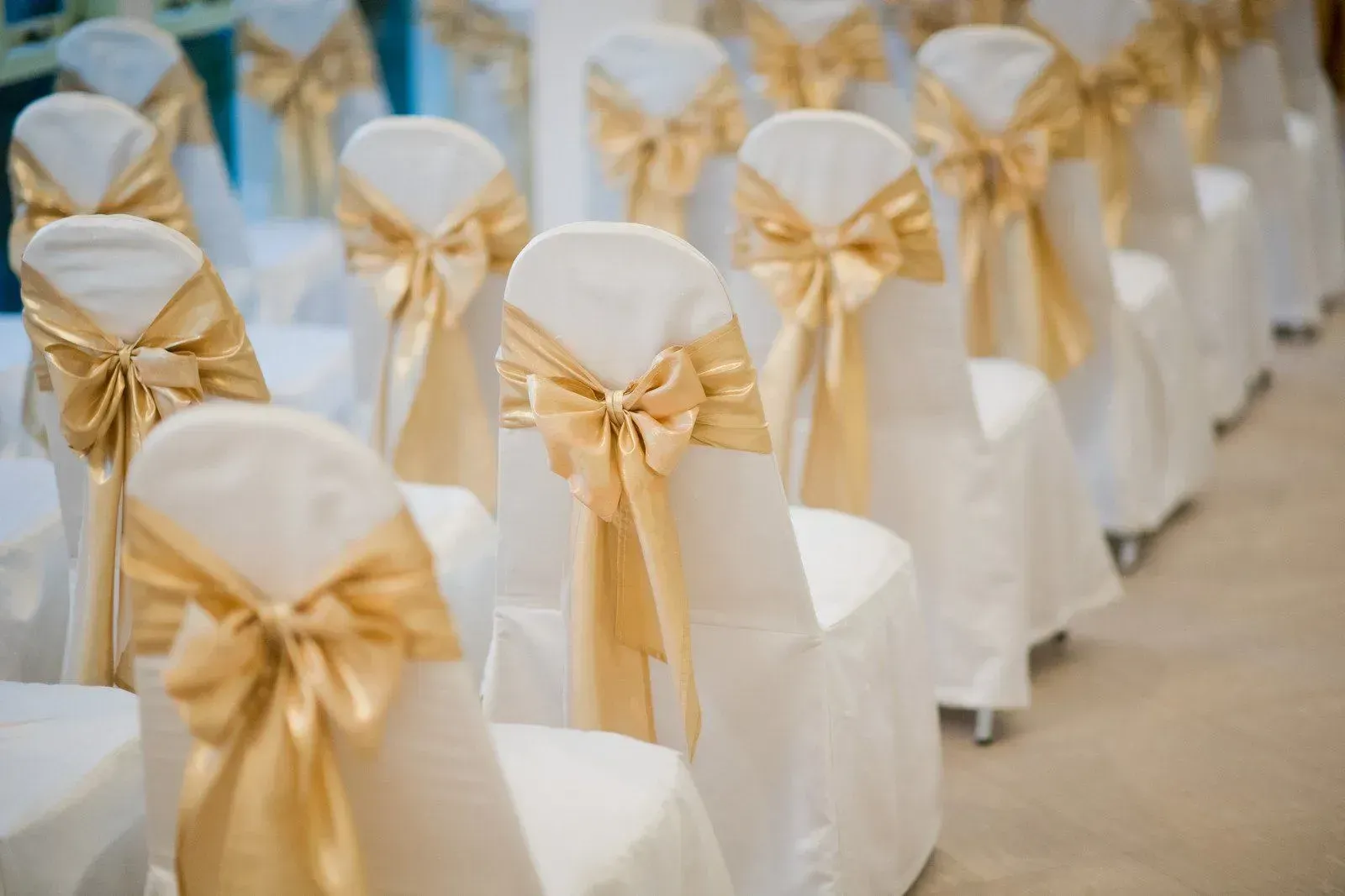 Rows of white chairs decorated with gold bows for a formal event