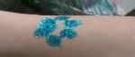 A person 's arm with a blue glitter tattoo on it.