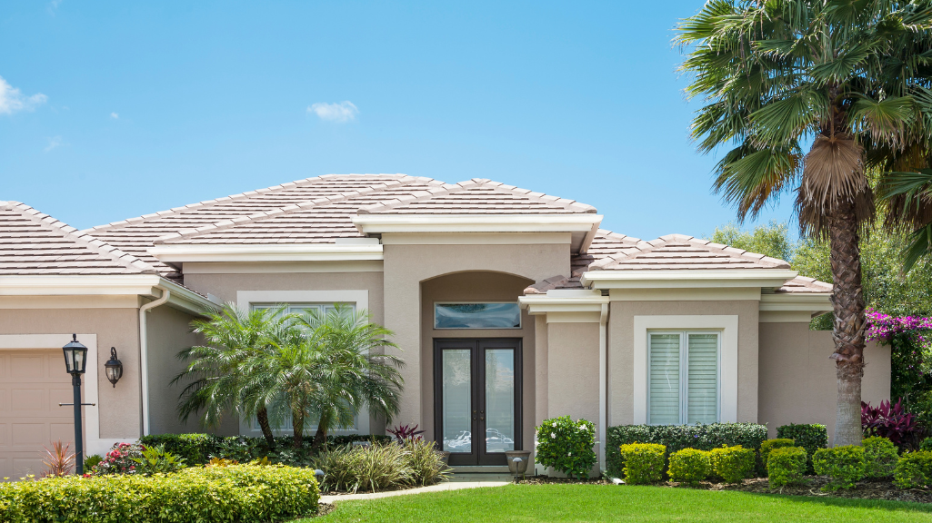 A large house with a lush green lawn and palm trees in front of it.