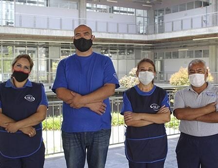 Un grupo de personas que llevan mascarillas están de pie una al lado de la otra.