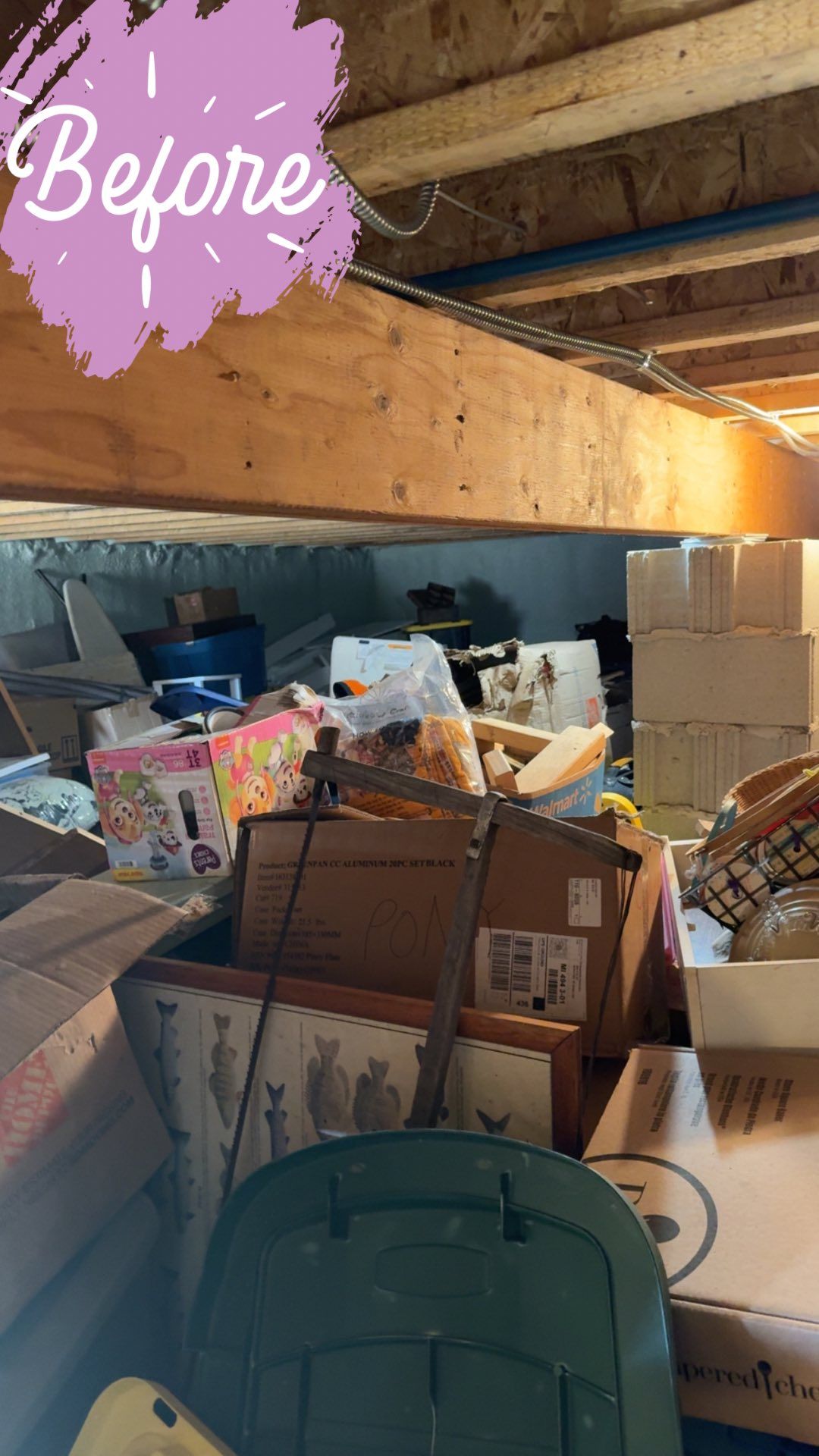 Cluttered basement with boxes, junk, and a storage bin under wooden beams.