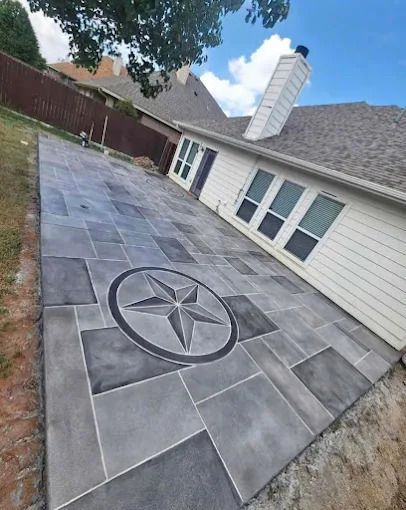 Gray concrete patio with a star design, adjacent to a light-colored house.
