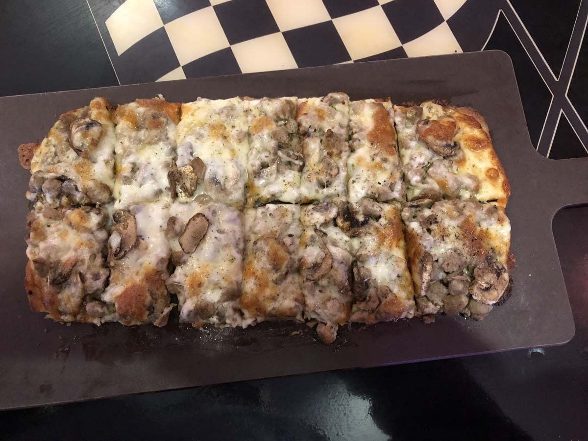 A pizza with mushrooms and cheese is on a cutting board.