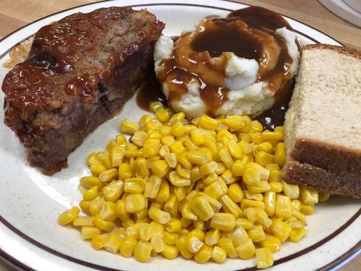 A white plate topped with meat loaf mashed potatoes corn and bread