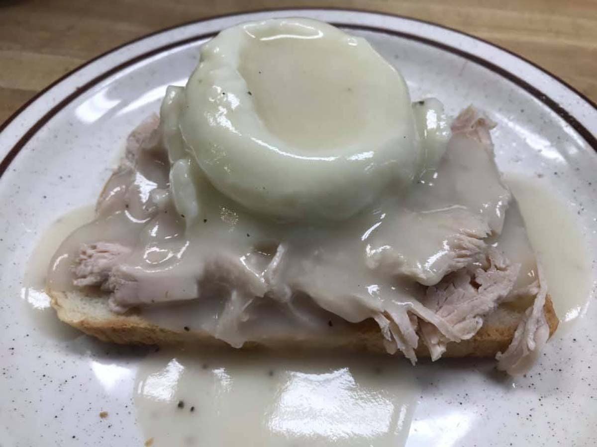 There is a poached egg on top of a piece of meat on a plate.