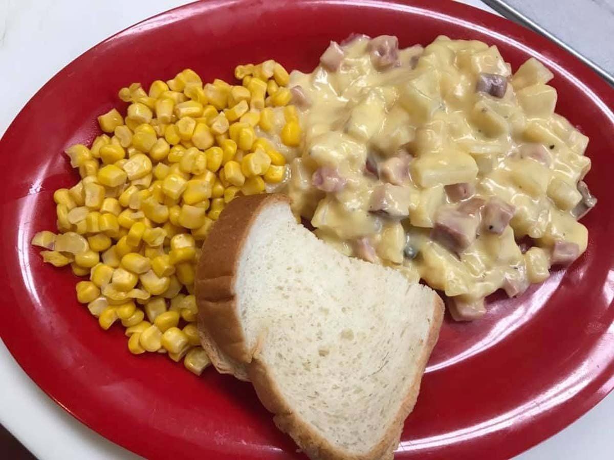 A red plate topped with macaroni and cheese corn and bread