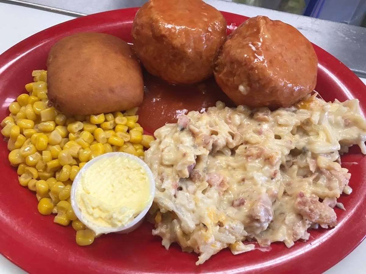 A red plate topped with meatballs , corn , mashed potatoes and eggs.