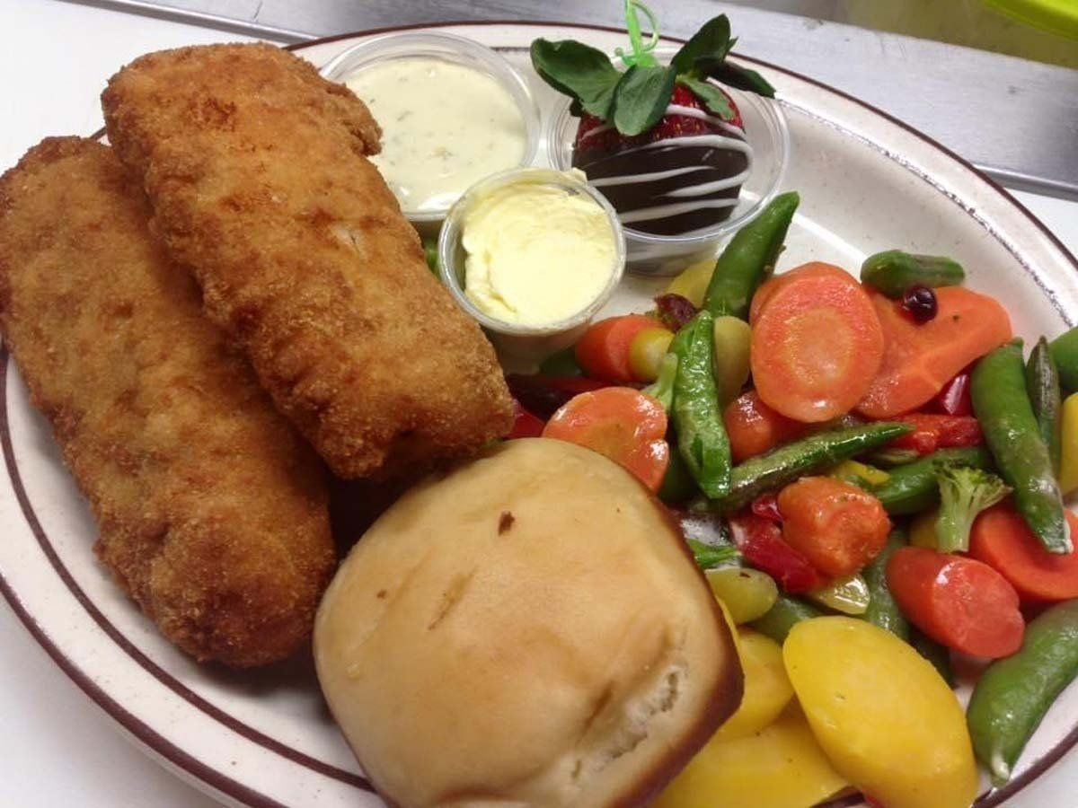 A white plate topped with fried fish and vegetables