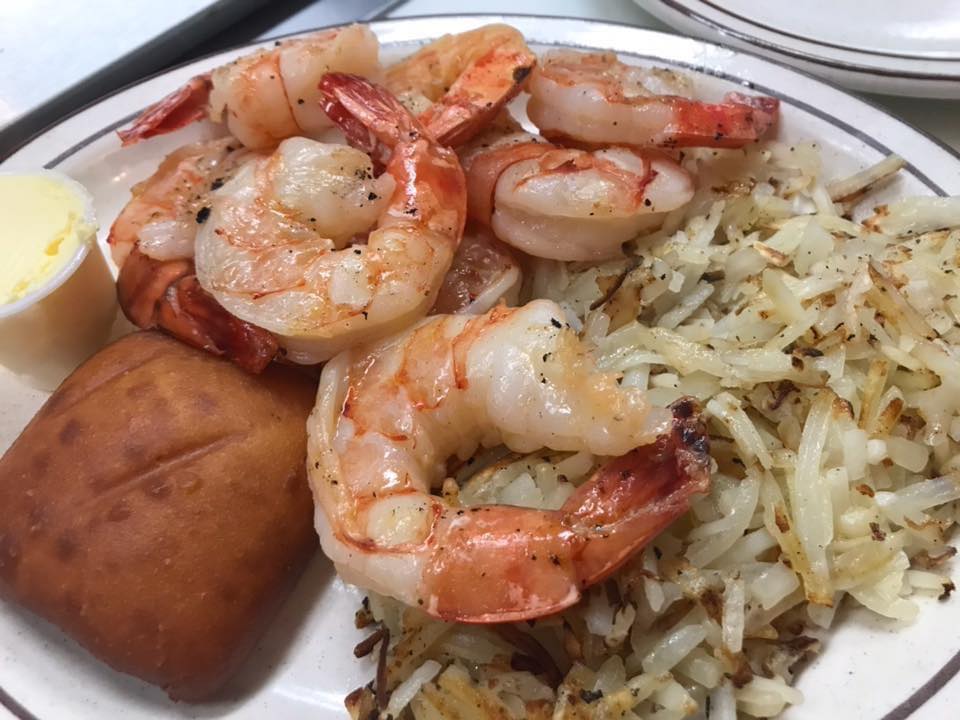A white plate topped with shrimp , hash browns and a doughnut.