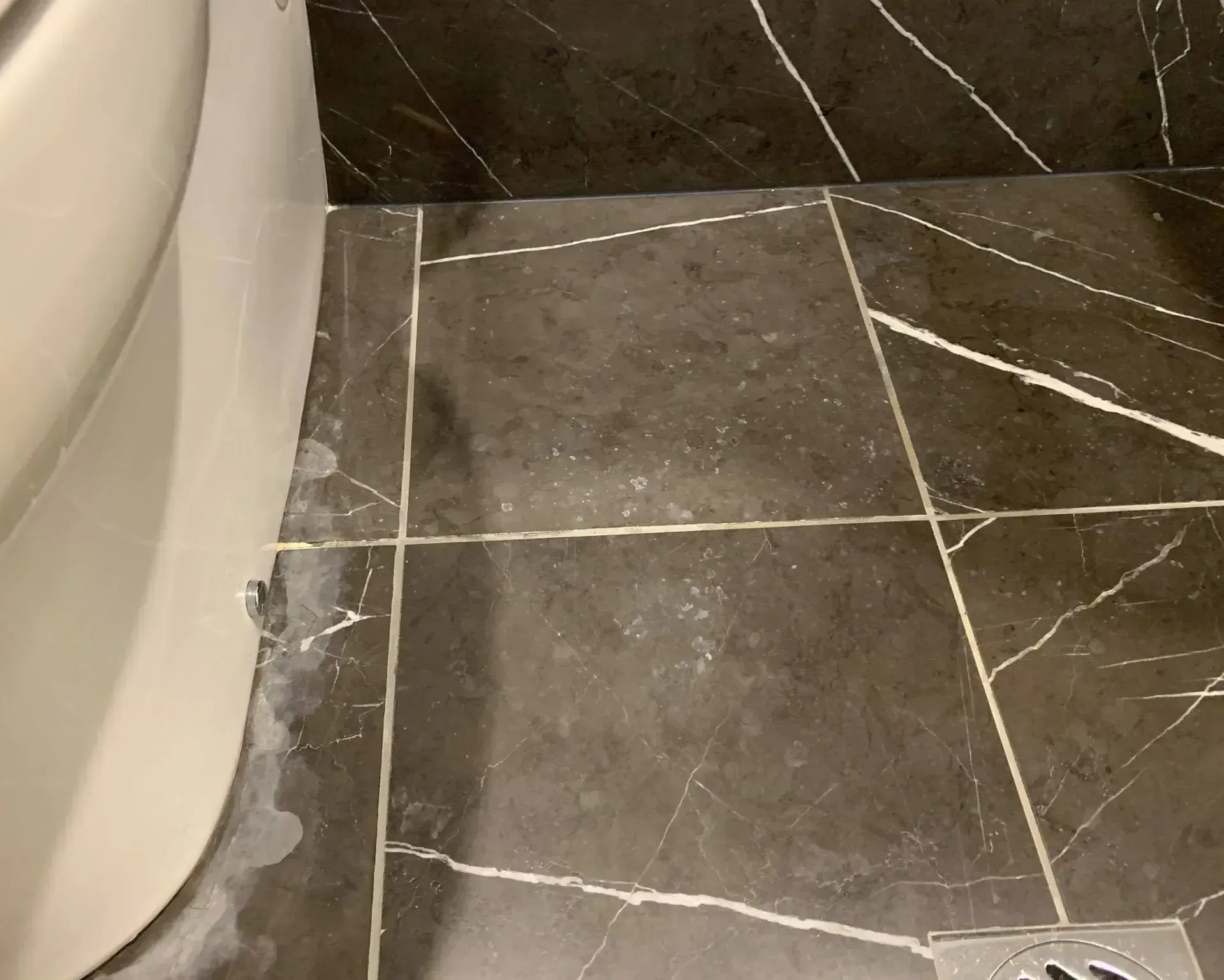 A bathroom floor with black tiles and a sink