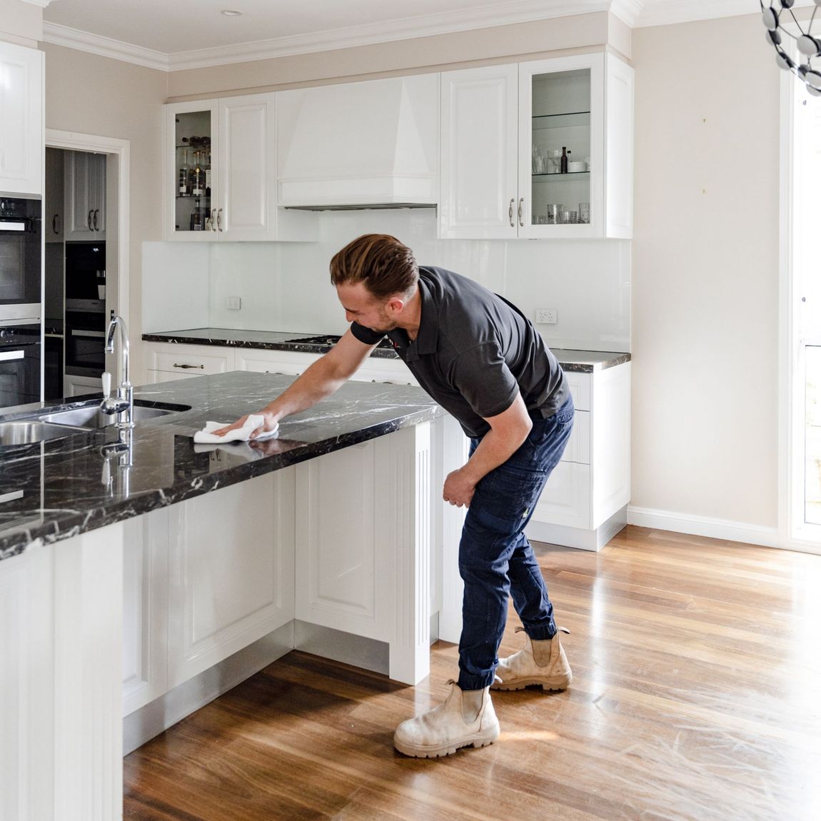 A man is cleaning a kitchen counter with a cloth.