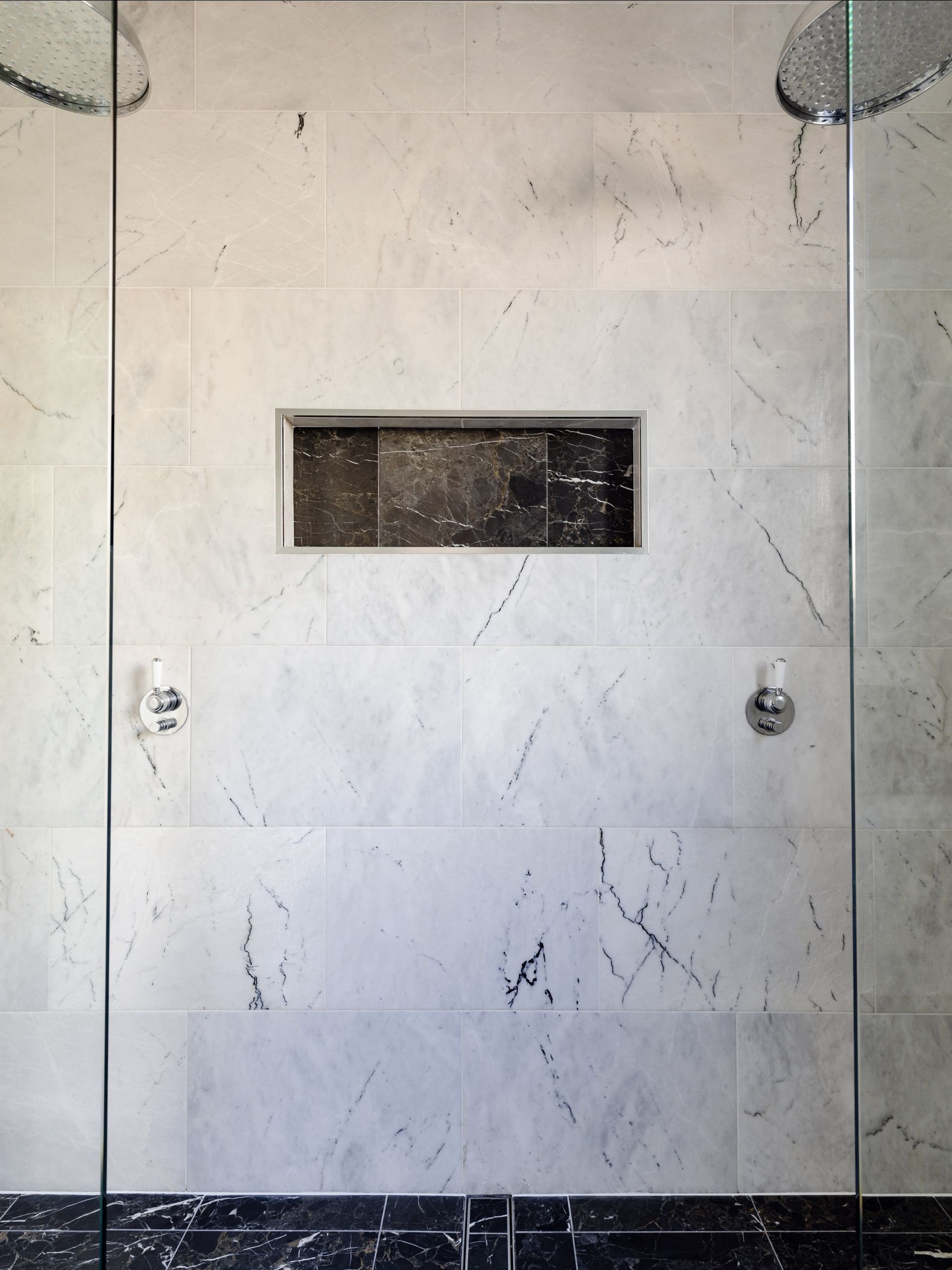 A bathroom with marble tiles and a shower head