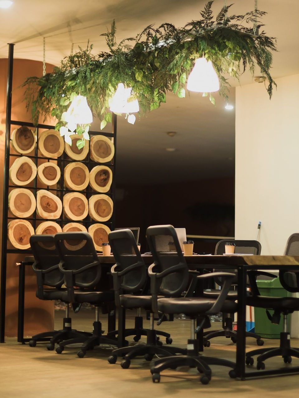 A conference room with tables and chairs and plants hanging from the ceiling