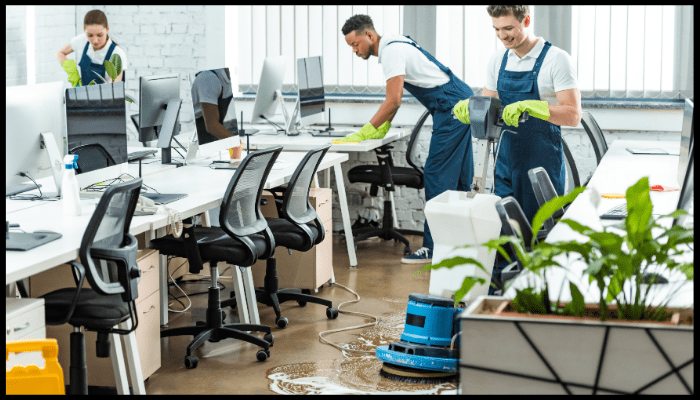 Professional cleaning team performing end of lease cleaning in a modern office space, polishing floors and sanitising desks.