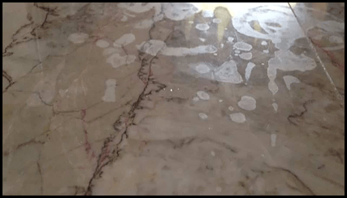 A close up of a marble floor with white spots on it.