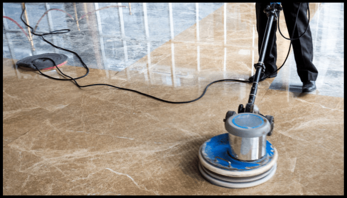 Technician polishing a marble floor using a professional restoration machine to remove scratches and etching.